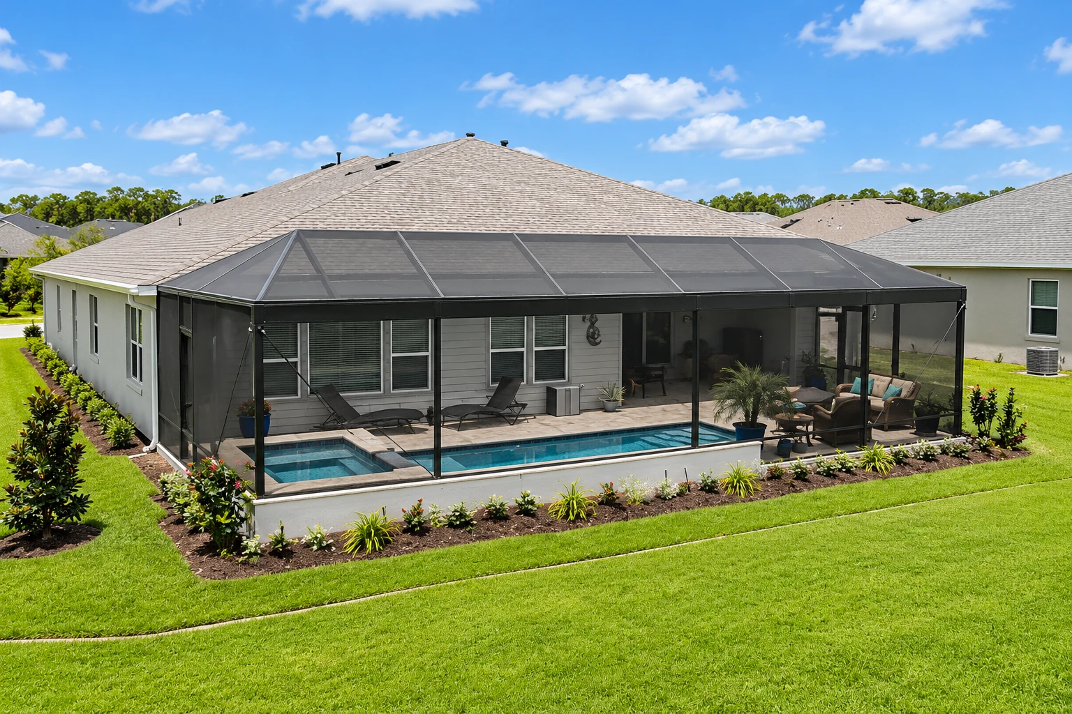 A large screened patio enclosure with a peaked roof surrounds a swimming pool behind a single-story home.