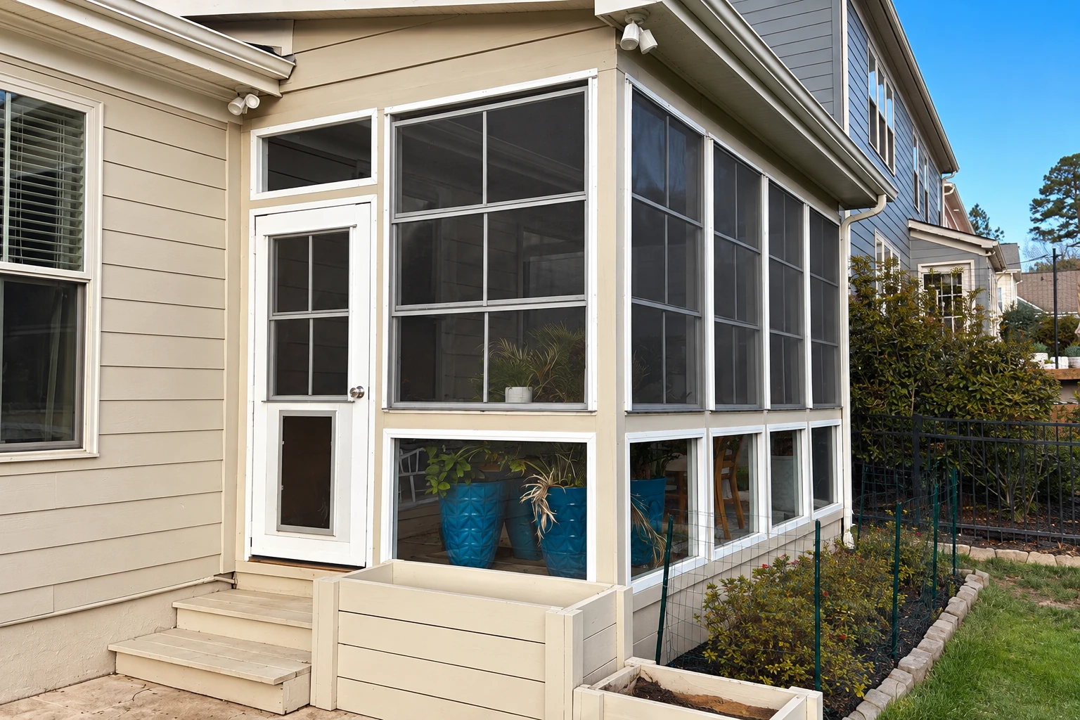 Enclosed patio sunroom with white framing, screened upper windows, a door and small entry steps.